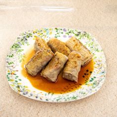 some food is sitting on a plate with sauce in the middle and it looks like spring rolls