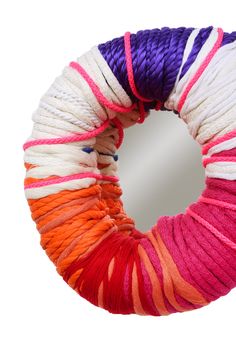 a round mirror with yarn wrapped around it