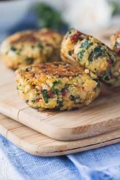 three crab cakes sitting on top of a wooden cutting board next to a blue towel