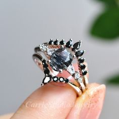 a woman's hand holding an engagement ring with black and white stones