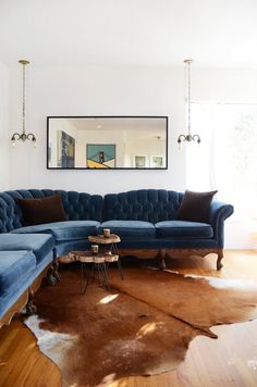 a living room filled with furniture and a cowhide rug on the floor in front of a large mirror