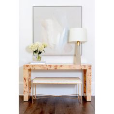 a white vase with flowers sitting on top of a wooden table next to a lamp