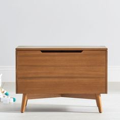 a wooden chest sitting on top of a white floor next to a stuffed animal toy