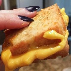 a hand holding a sandwich with cheese on it