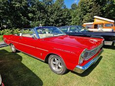 an old red car is parked in the grass near other classic cars on display at a car show