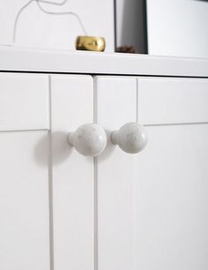 a white cabinet with two knobs on the front and one door handle is shown