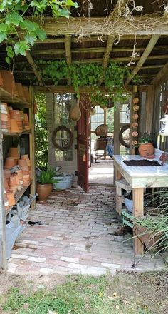 an outdoor garden shop with pots and plants on the shelves, in front of a brick walkway