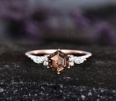 an engagement ring with a brown diamond and three white diamonds on the side, sitting on top of a black rock