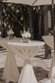 the table is set up with white flowers and umbrellas for an outdoor wedding reception