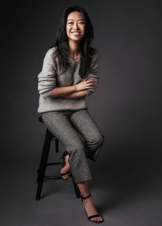 a woman sitting on top of a stool smiling