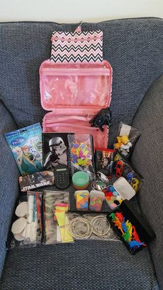 an open pink case sitting on top of a couch filled with toys and other items