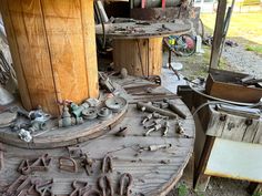 an old wooden table with various tools on it and other items scattered about in the yard