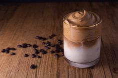 a glass filled with milk and coffee beans on top of a wooden table