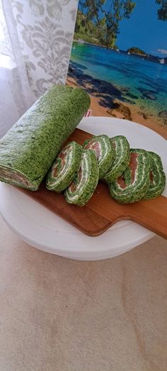 some food is laying out on a wooden cutting board next to a card with the ocean in the background