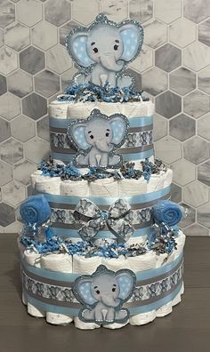 a three tiered diaper cake with an elephant on top and blue ribbon around the edges