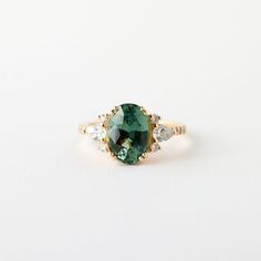 a green and white diamond ring on a white surface