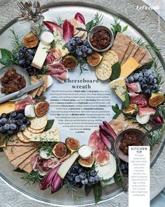 a platter filled with cheeses, crackers and fruit on top of a table