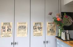 a vase filled with flowers sitting on top of a counter next to two white cupboards