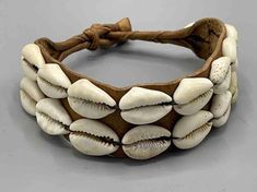 These traditional bracelets were worn by both men and women for protective purposes, as well as personal adornment. The leather, made from goatskin, would have contained items of medicinal or spiritual value which defend the wearer from whatever he or she may consider to be threatening to them. Cowrie shells, prior to European occupation, were currency and so still reflect their former significance. The clasp for each is the traditional ball and loop style. These cowrie shells are the real thing Bohemian Jewelry With Leather Strap, Traditional Leather Bracelet, Traditional Adjustable Leather Jewelry, Adjustable Traditional Leather Bracelet, Traditional Leather Jewelry For Festival, Traditional Adjustable Leather Bracelet For Festivals, Cowrie Shells, Clasp Bracelet, He Or She