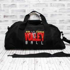 a black duffel bag sitting on top of a wooden floor next to a white brick wall