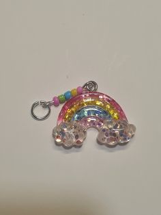 a key chain with a rainbow charm hanging from it's side on a white surface