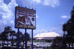 a large sign for circus world in front of a building with a domed roof and palm trees