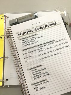 an open notebook with writing on it sitting next to a yellow binder and pen