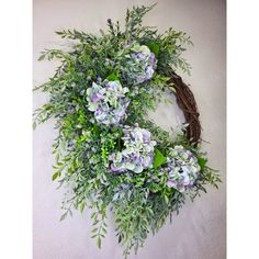 a wreath with purple and white flowers hanging on a wall