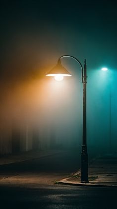 a street light sitting on the side of a road next to a parking lot covered in fog