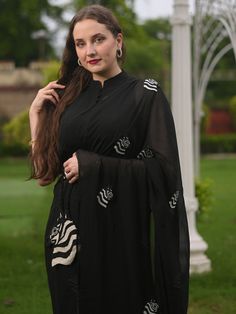 This is a three-piece black zebra saree set from the Ensembles collection. The black zebra saree is paired with a black sleeveless blouse. The blouse has front potli button opening, and a mandarin collar. There are beautiful zebra motifs of black and white bead work all over the saree. This saree set is crafted in pure organza fabric with contrast piping border. The outfit is completed with a heavily embellished, beadwork black and white zebra shape handbag. Elegant Black Pre-draped Saree With Mirror Work, Designer Sheer Dupatta Blouse In Black, Designer Black Blouse With Sheer Dupatta, Black Sets For Evening Eid Celebration, Black Evening Sets For Eid, Designer Black Blouse With Dupatta, Black Blouse With Traditional Drape For Eid, Black Traditional Drape Blouse For Eid, Black Blouse With Dupatta For Eid