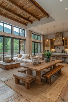 a large open living room and dining area with wood beams on the ceiling, hardwood flooring