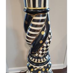 a large black and white vase with gold dots on it's sides sitting on top of a table