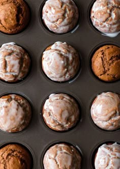 twelve muffins with frosting in a baking pan