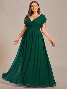 a woman in a green dress posing for the camera with her hands on her hips