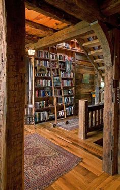 the inside of a log cabin with bookshelves and stairs leading up to it