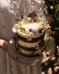 a person holding a cake with flowers on it