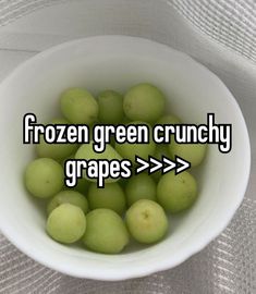 a white bowl filled with green grapes on top of a table