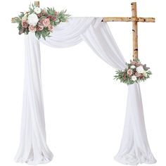 a cross decorated with flowers and greenery on top of a white cloth covered altar