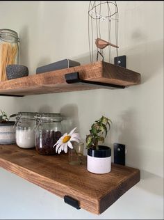 two wooden shelves with jars and flowers on them