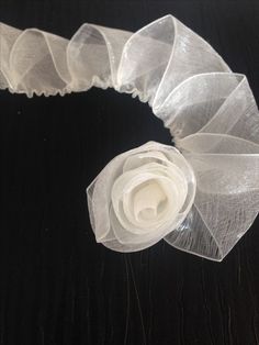 a close up of a white flower on a black surface with sheer netting around it