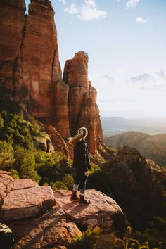 a woman standing on top of a rock formation