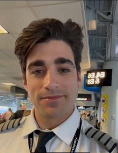 a man wearing a white shirt and black tie in an airport with people walking around