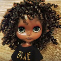 a doll with curly hair wearing a t - shirt that says bowlie on it