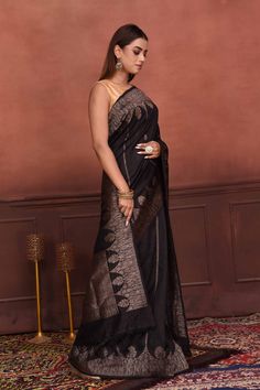 Radiate elegance on festive occasions in this stunning black tussar Banarasi saree with antique zari work. It comes with a red blouse piece. Disclaimer: The shown stitched blouse on the model is for display purpose only. The saree comes with a matching blouse piece and finished with fall and piko. Disclaimer: The actual product may vary slightly from the image. These are custom orders, hence expect slight variation in color, placement of the motif or buta. ESTIMATED DELIVERYBecause this is a cus Black Art Silk Pre-draped Saree With Zari Weaving, Designer Black Banarasi Silk Saree, Black Bollywood Handloom Pre-draped Saree, Designer Black Tussar Silk Saree, Black Pre-draped Saree With Zari Weaving In Art Silk, Black Dupatta With Zari Weaving For Designer Wear, Black Art Silk Saree With Zari Work, Elegant Black Slub Silk Traditional Wear, Designer Black Banarasi Silk Blouse Piece