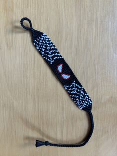 a black and white knitted lanyard with an evil face on it's side