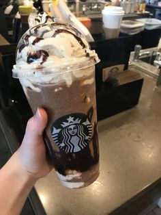 a hand holding up a starbucks drink with whipped cream and chocolate