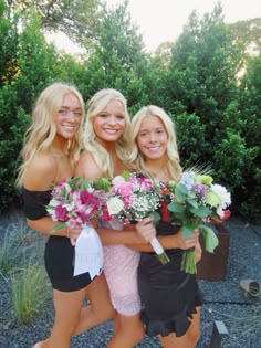 three beautiful young women standing next to each other holding bouquets in their hands and smiling at the camera