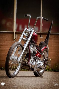 a red and black motorcycle parked in front of a brick building