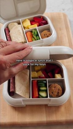 someone is holding their lunch box open to show it's compartments filled with food