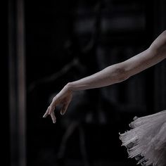 a ballerina in a white tutu with her arm extended and one hand out